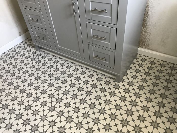 Patterned star-mosaic tile bathroom floor around a gray vanity