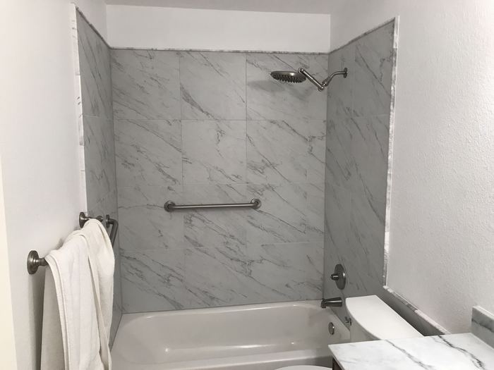 Re-tiled tub surround with marble-look tile, new fixtures and safety bar