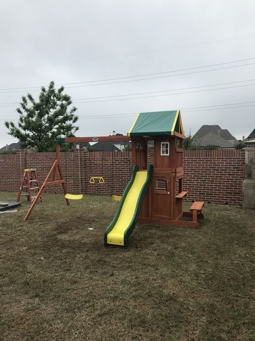 Assembled wooden swing set with slide and canopy in a backyard