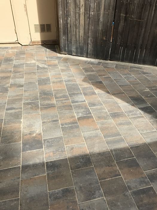 Multi-color slate-look paver patio laid in straight courses beside a wood fence